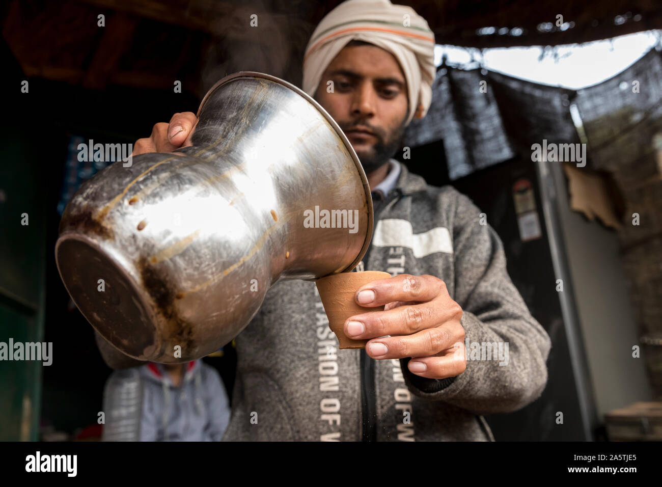Un 'Rajasthani Chaiwalla' uomo versa il tè in una tradizionale tazza di argilla. Foto Stock