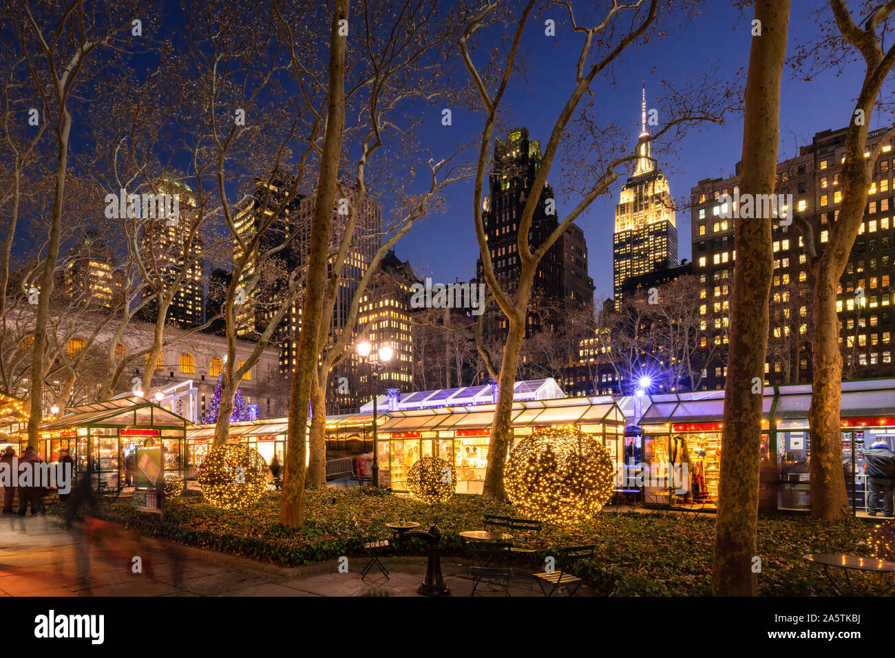 Bryant Park Winter Village (Mercatino di Natale) in serata con l' Empire State Building in background. New York City, NY, STATI UNITI D'AMERICA Foto Stock