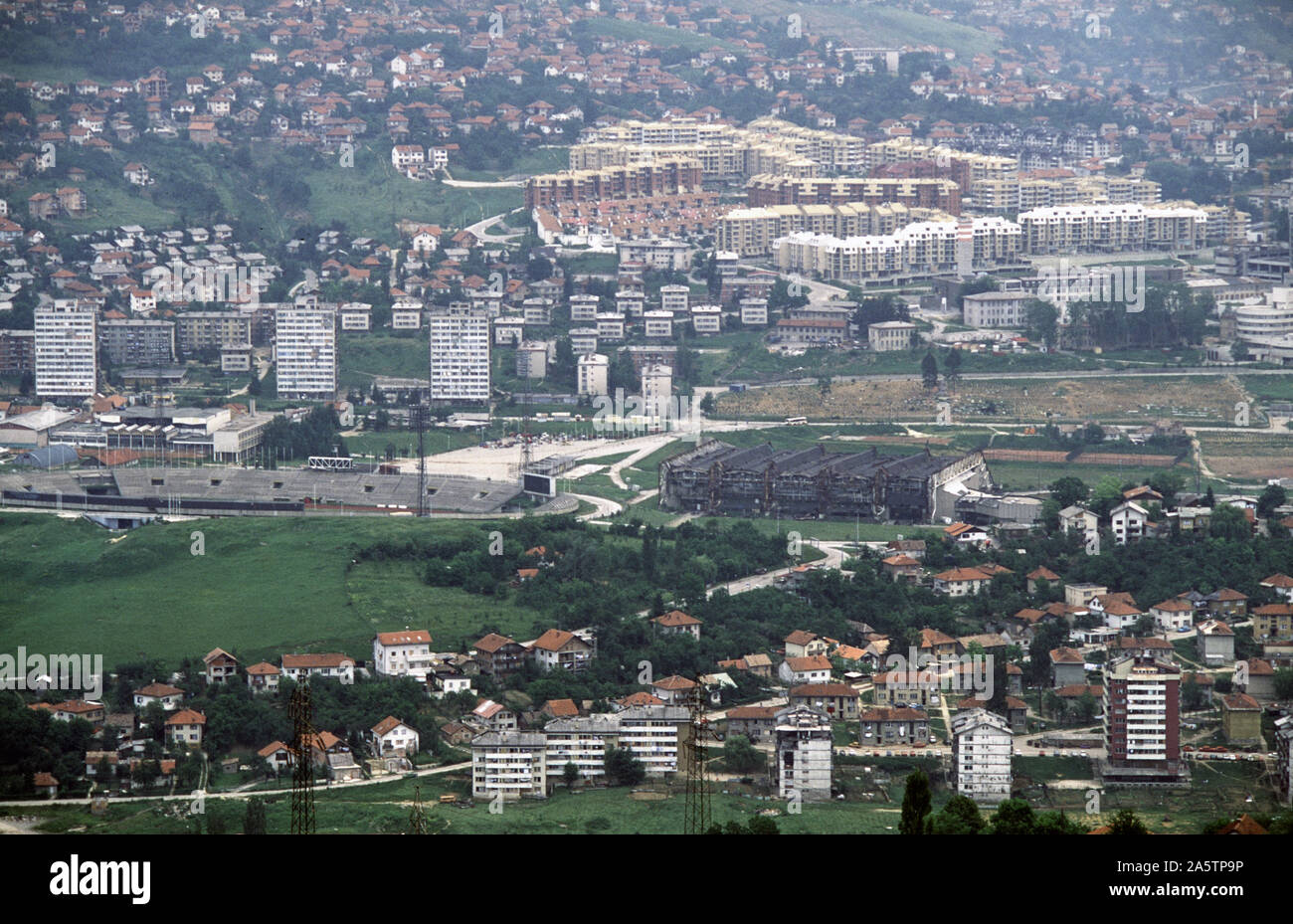 6 Giugno 1993 durante l'assedio di Sarajevo: la vista a est dalla collina di ronzio. Il Koševo City Stadium è sulla sinistra e il bruciato Juan Antonio Samaranch Olympic Hall (precedentemente noto come Zetra Olympic Hall) di centro-destra. Immediatamente sopra la sala è il 'Lion' cimitero. Foto Stock