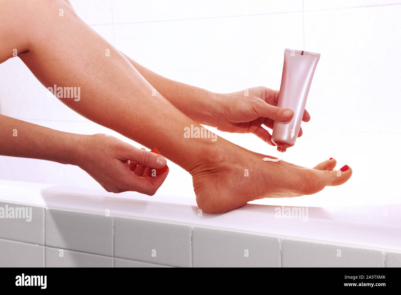 Gamba di donna. L'applicazione di crema piedi. Trattamento sano. Foto Stock