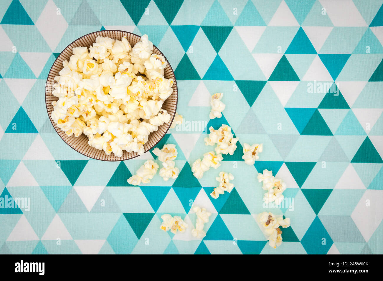 Pop corn in un recipiente isolato su bianco e lo sfondo blu Foto Stock