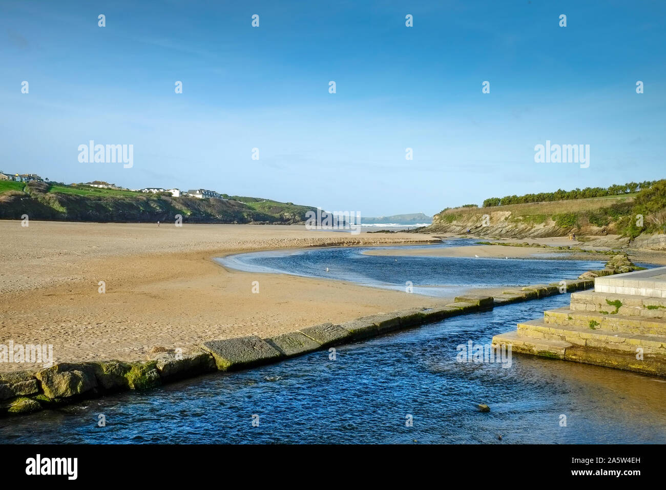 Un fiume che scorre verso il mare sulla Porth Beach in Newquay in Cornovaglia. Foto Stock