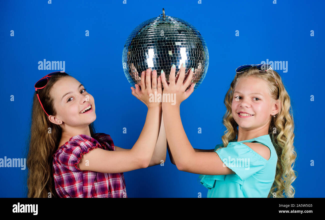 Holiday celebrazione. Concetto di intrattenimento. Sorelle amici con palla da discoteca. Iniziare a parte. Allegro kids tenere palla da discoteca. Discoteca danze. Musica retrò. Gli specchi riflettenti discoteca luci di atmosfera. Foto Stock