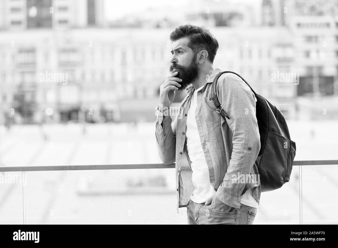 Il concetto di viaggio. Turisti in vacanza. Hipster turista moderno background urbano. In cerca di avventure. Tourist bello pensieroso hipster zaino. Uomo con la barba e zaino esplorare la città. Foto Stock