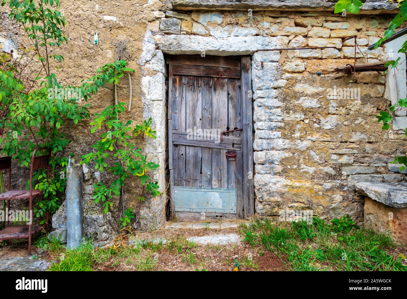 Il vecchio blocco porta di legno su una pietra fattoria abbandonata. Immagine Foto Stock