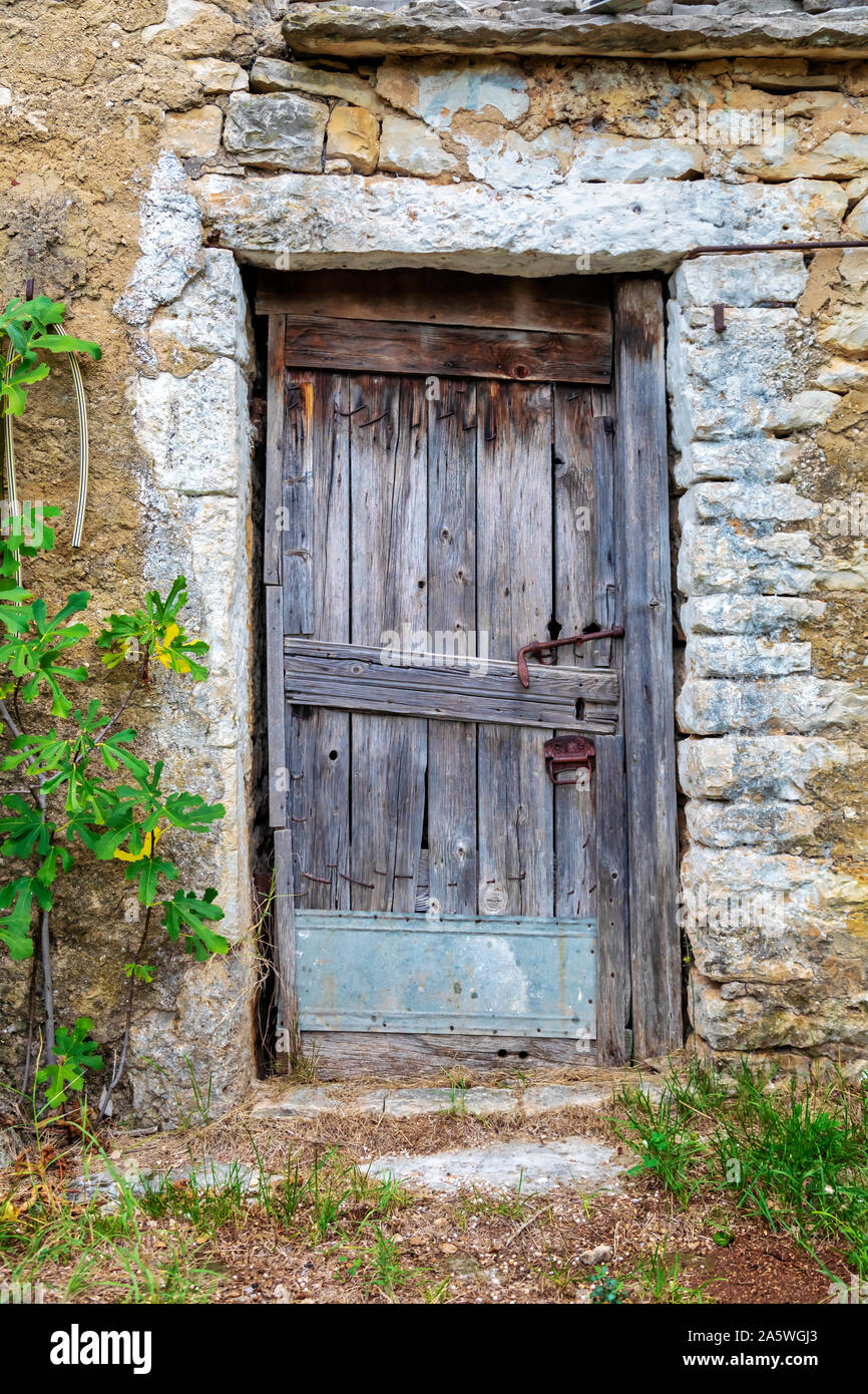 Il vecchio blocco porta di legno su una pietra fattoria abbandonata. Immagine Foto Stock