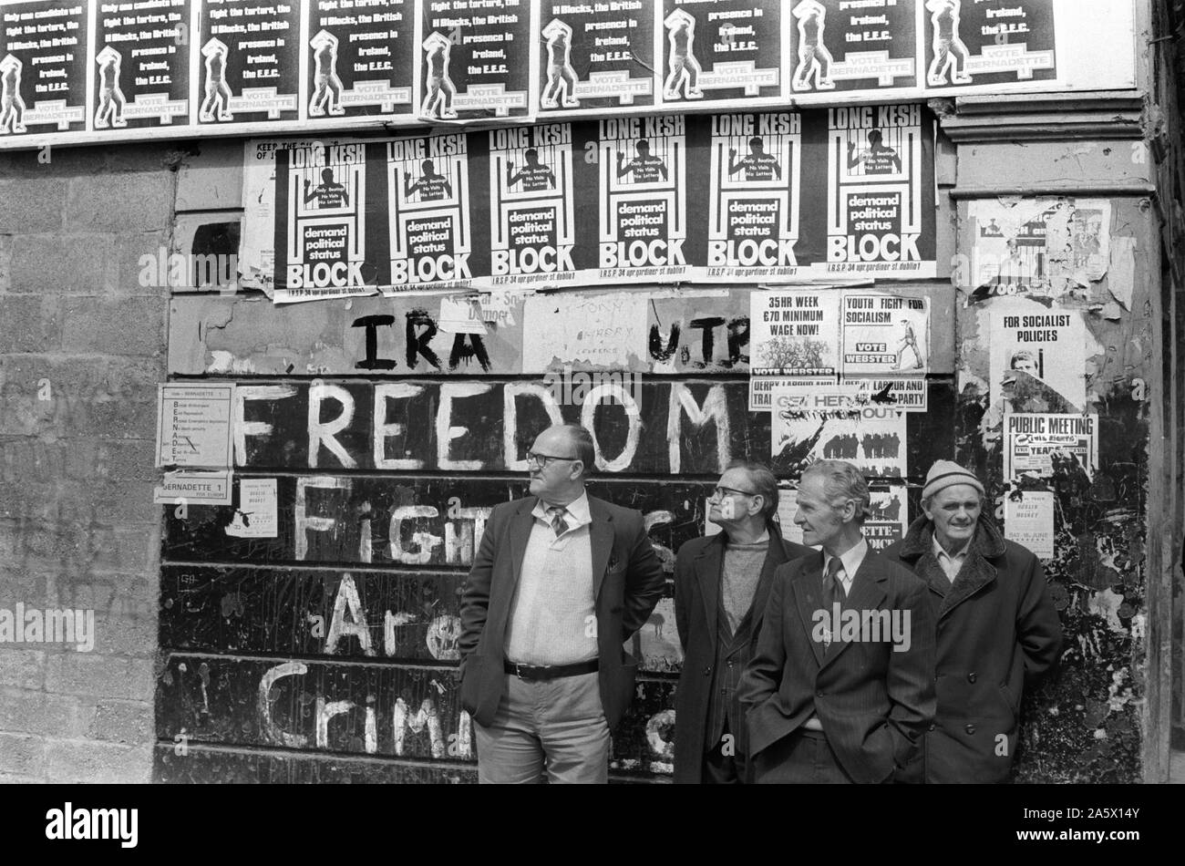 Derry Irlanda del Nord Londonderry 1979. I problemi degli anni settanta uomini disoccupati centro città passando il tempo di giorno in piedi sotto il poster per lunghi Kesh H blocco combattenti per la libertà non sono criminali scritto sulla parete. 70S UK HOMER SYKES Foto Stock