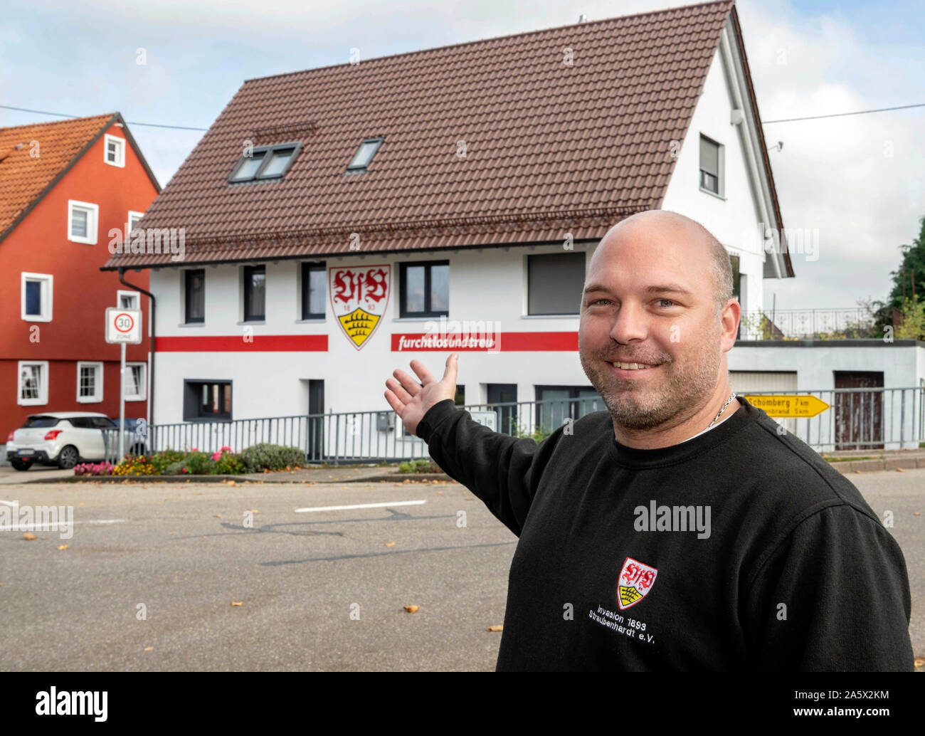 22 ottobre 2019, Baden-Wuerttemberg, Neuenbürg: Michael La Neuweiler sorge nella parte anteriore della sua casa che egli ha verniciato nei colori rosso-bianco e il club stemma della seconda league club VfB Stuttgart. La Neuweiler è stata la ristrutturazione della casa per tre anni dopo che la riprendono da sua nonna. Ora è stata la facciata di turno. La Neuweiler è stato un fan del club di Stoccarda per dieci anni ed è stato anche presidente del VfB fan club 'invasione 1893 Straubenhardt' per un paio di settimane. Foto: Uli Deck/dpa Foto Stock