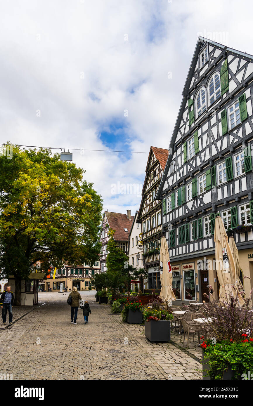 Schorndorf, Germania, 10 ottobre 2019, la gente camminare su piazza in ciottoli a fianco idilliaco case con travi di legno di antichi marketplace in downtown sch Foto Stock