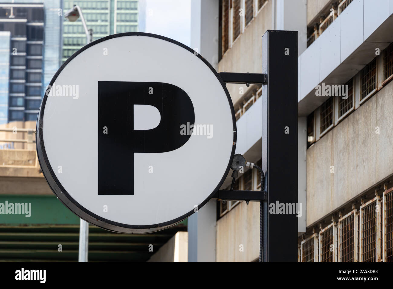 Cartello parcheggio (P) su palo davanti ad un garage in una grande città. Foto Stock