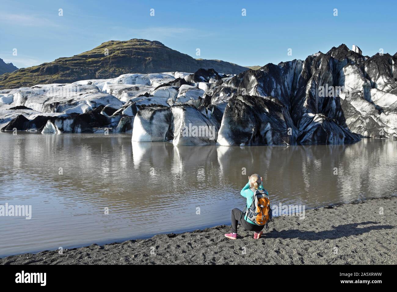 Escursionista prende le immagini del ghiacciaio Solheimajokull, Solheimajokull, lingua del ghiacciaio di Myrdalsjokull compresi ceneri vulcaniche, vicino anello stradale Foto Stock