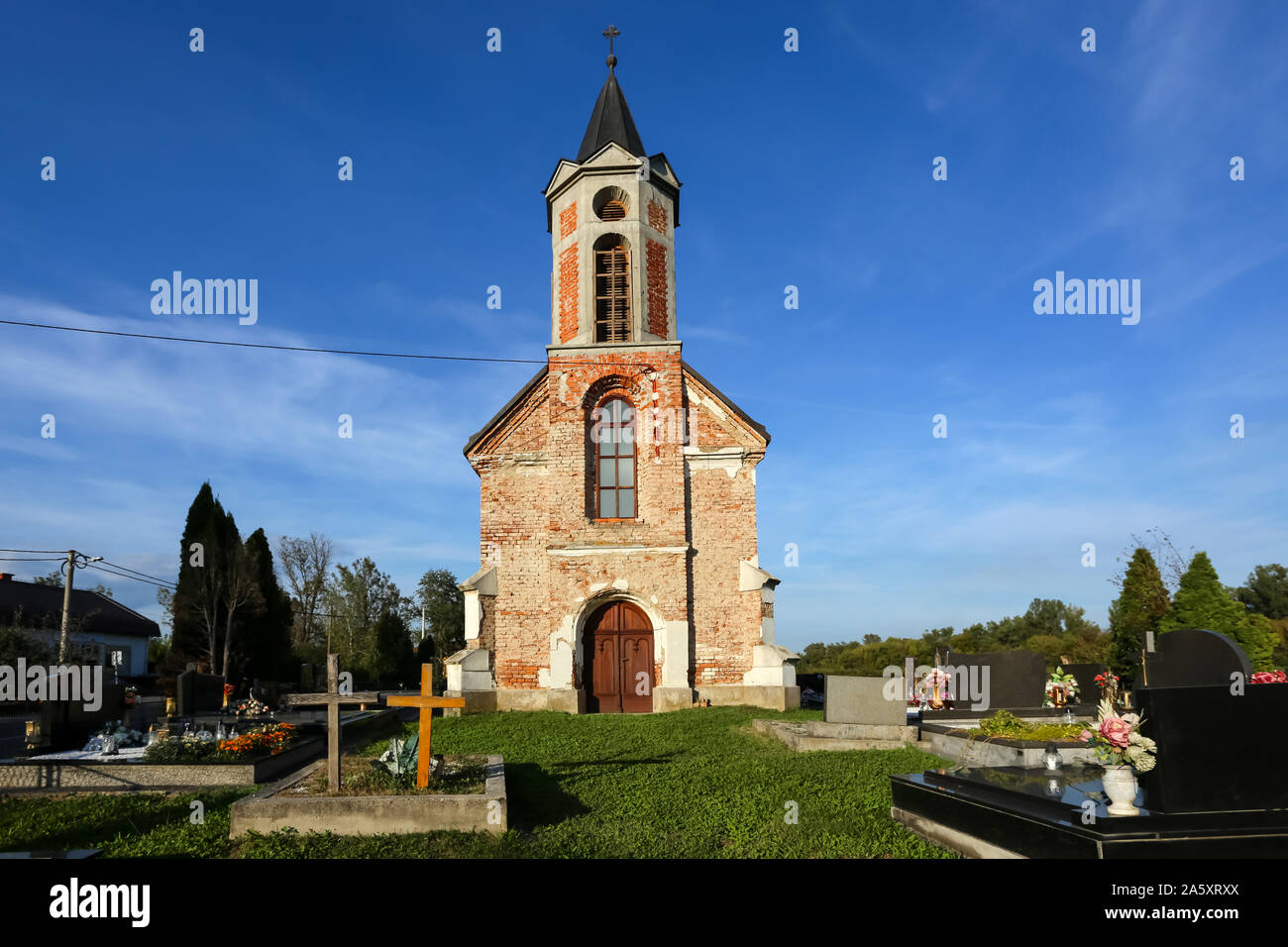 Blatnica Pokupska, Croazia - 14 Settembre 2019 : una piccola parete di mattoni chiesa cattolica sul cimitero durante il giorno. Foto Stock