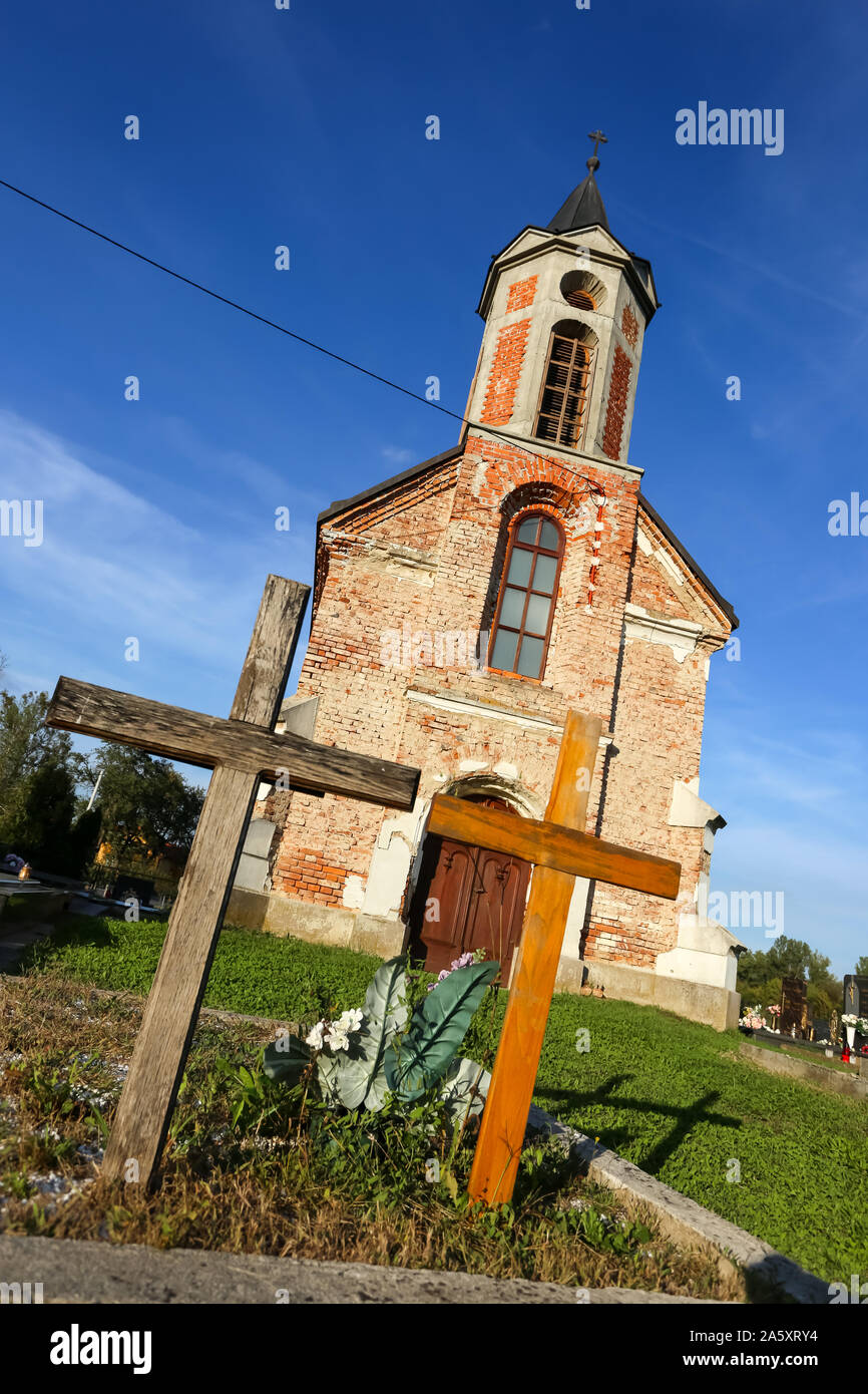 Blatnica Pokupska, Croazia - 14 Settembre 2019 : una piccola parete di mattoni chiesa cattolica sul cimitero durante il giorno. Foto Stock
