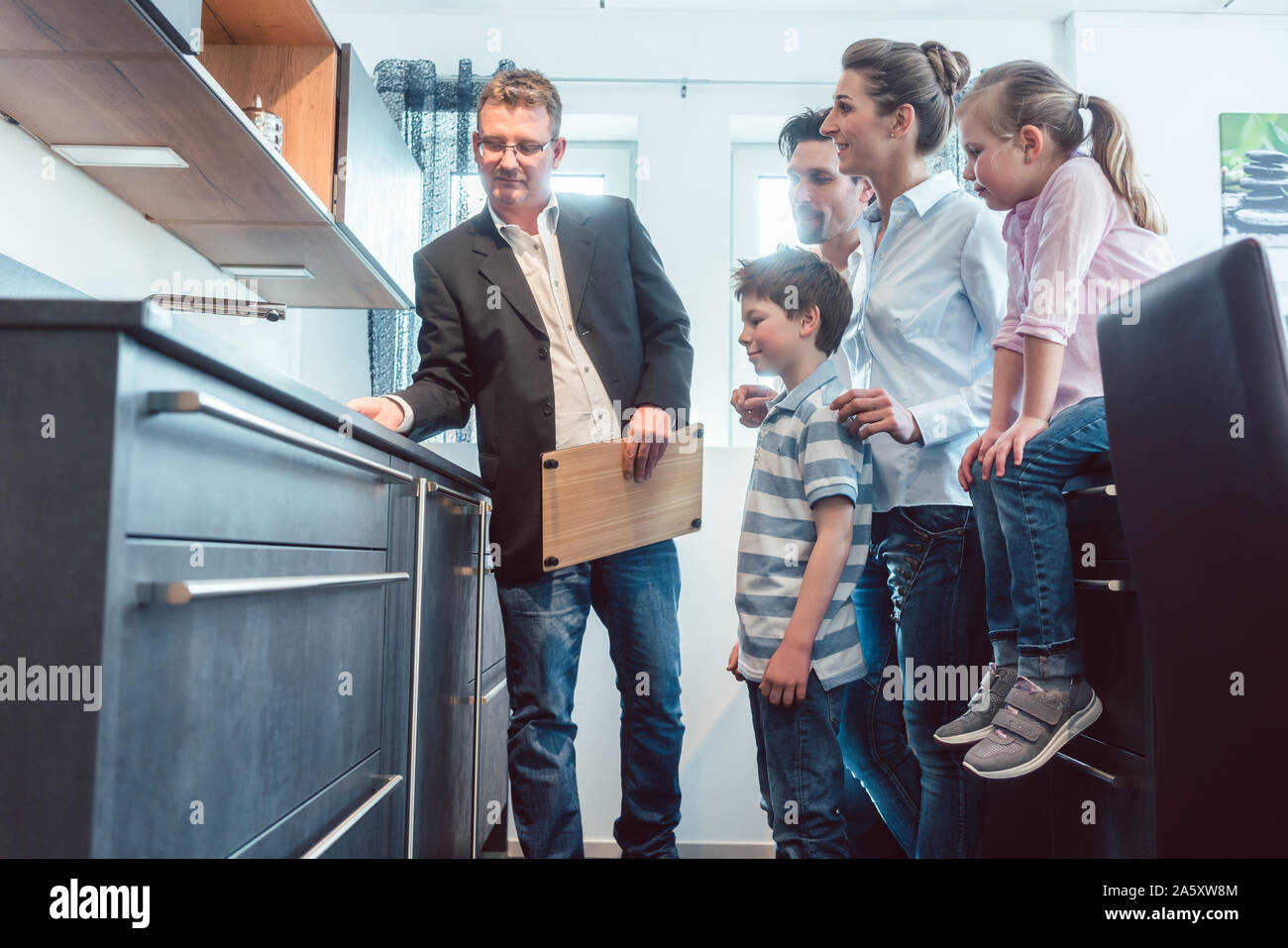 Venditore di famiglia che mostra le caratteristiche di una nuova cucina Foto Stock