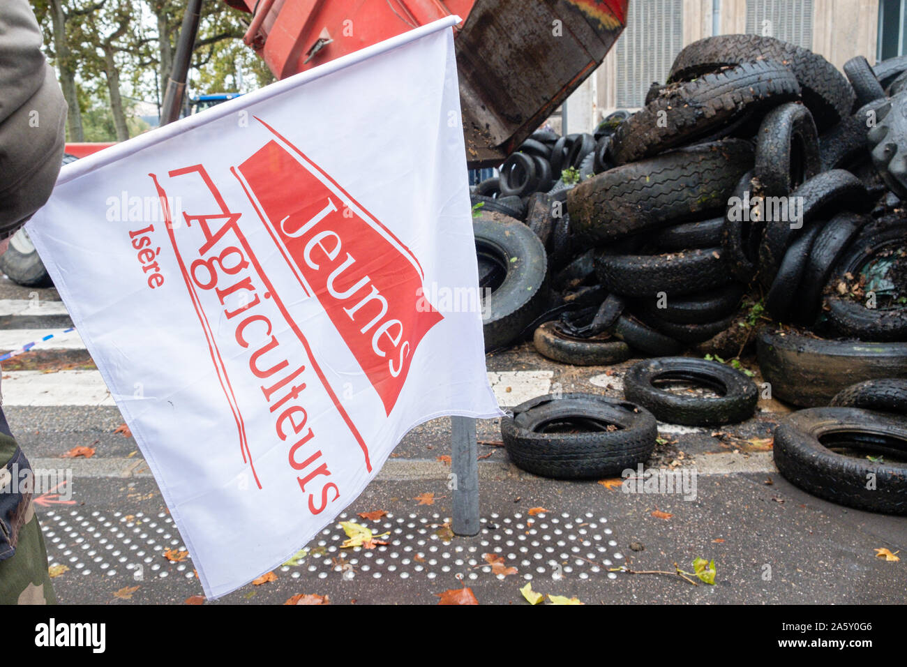 Ottobre 22, 2019, Lione, Auvergne-Rhône-Alpes, Francia - Dimostrazione di agricoltori. I giovani agricoltori' bandiera e la fuoriuscita dei pneumatici da parte dei dimostranti Foto Stock