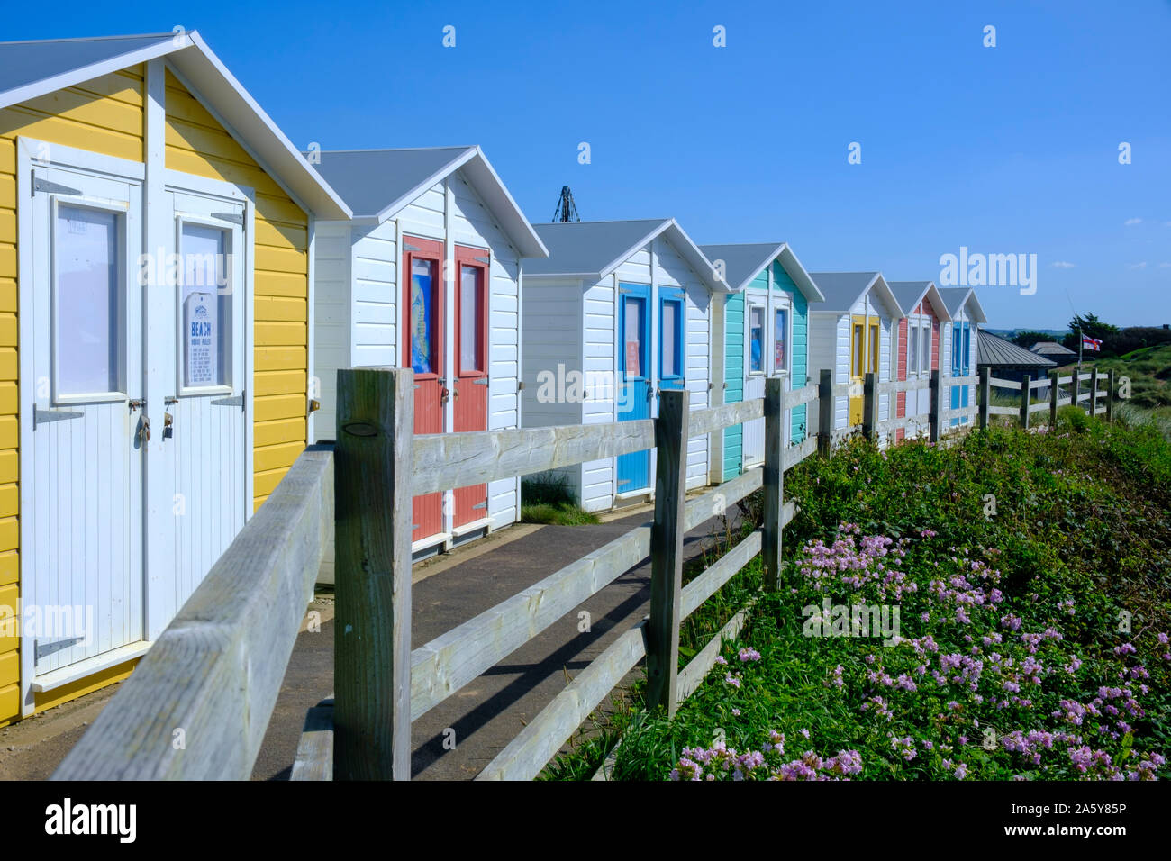 Multi colore capanne sulla spiaggia con il lungomare di fronte alla spiaggia a Bude Cornwall Inghilterra Foto Stock