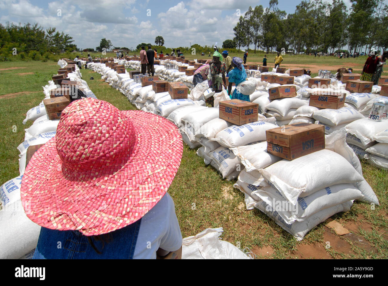 UGANDA, Kitgum , programma alimentare mondiale, distribuzione di mais e lattine USAID con olio vegetale per rifugiati sfollati interni della guerra civile tra LRA e esercito ugandese, donna con cappello di paglia rosso Foto Stock