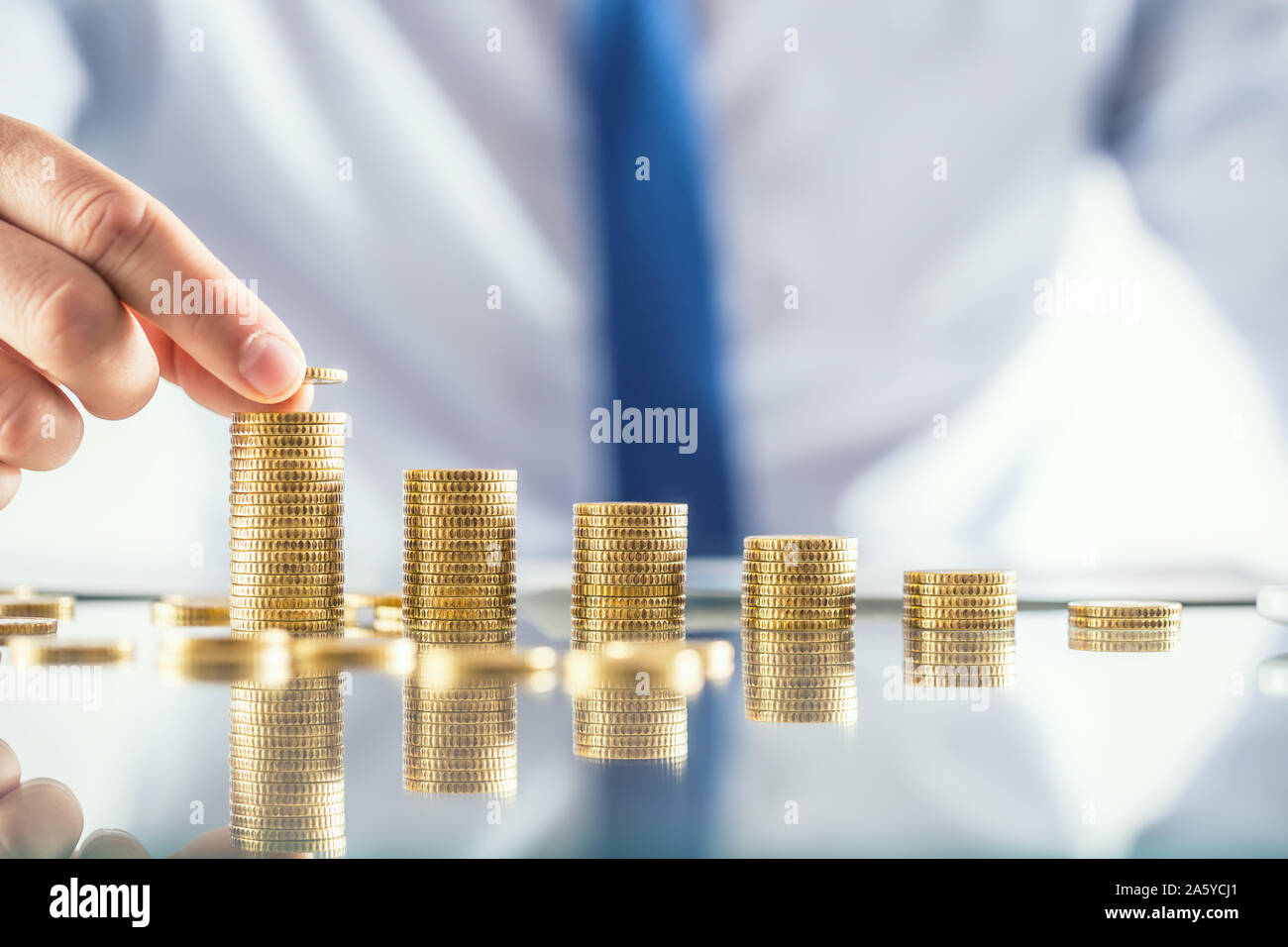 Banchiere commercialista o assicuratore costruisce grafico finanziario da monete d'oro. Foto Stock
