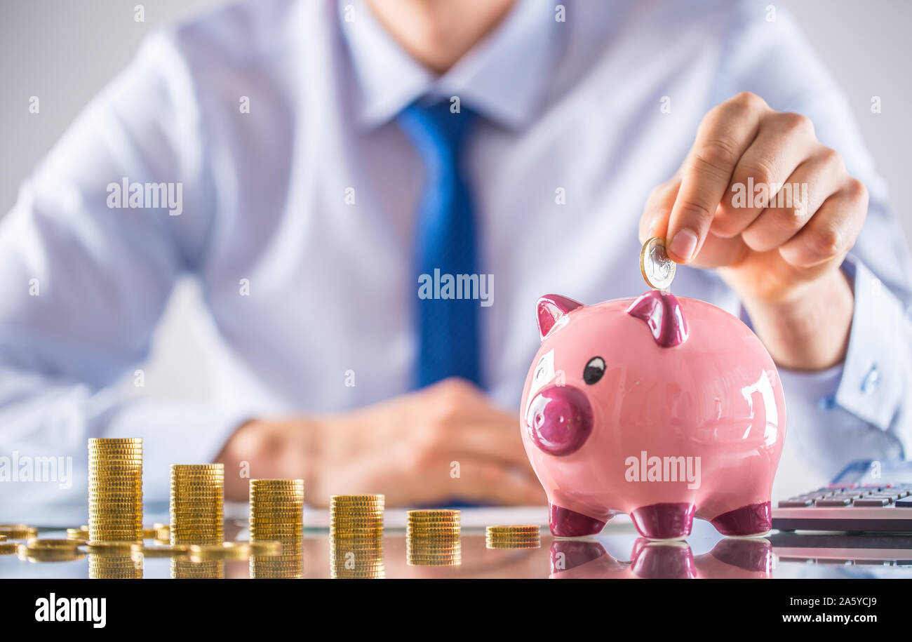 Banchiere commercialista o assicuratore mettere soldi in un salvadanaio. Tabella finanziaria da monete concetto aziendale Foto Stock