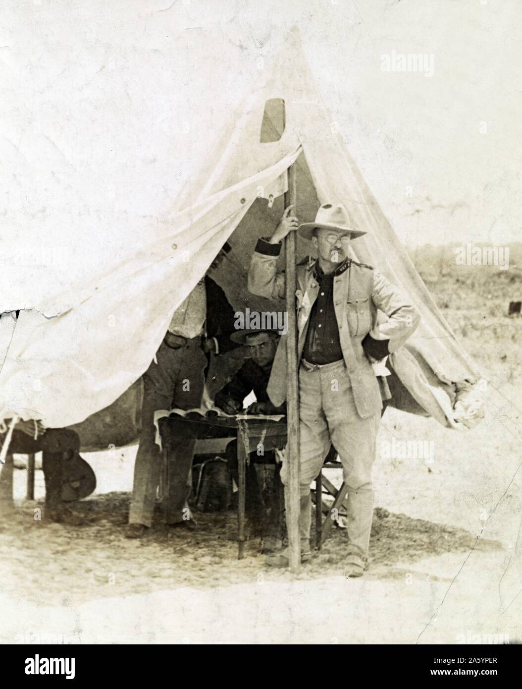 Stampa fotografica di Theodore Roosevelt (1858-1919) come un pilota ruvida, a Camp Wikoff in piedi nella parte anteriore della tenda con due uomini non identificati dietro di lui a Tampa, Florida. Fotografata da Underwood & Underwood fotografia. Datata 1898 Foto Stock