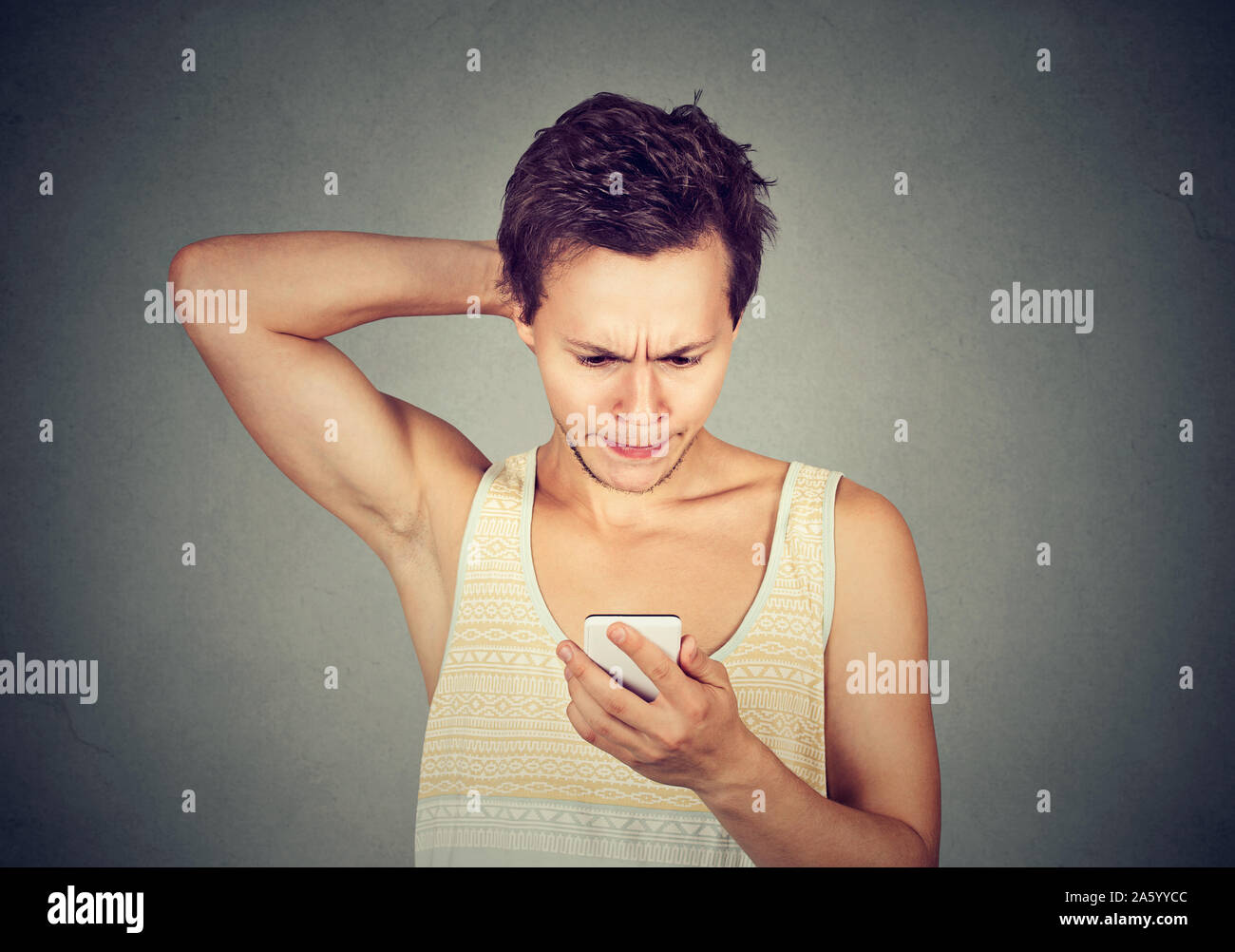 Ritratto di un giovane uomo che guarda un telefono cellulare con espressione confusa sul viso Foto Stock