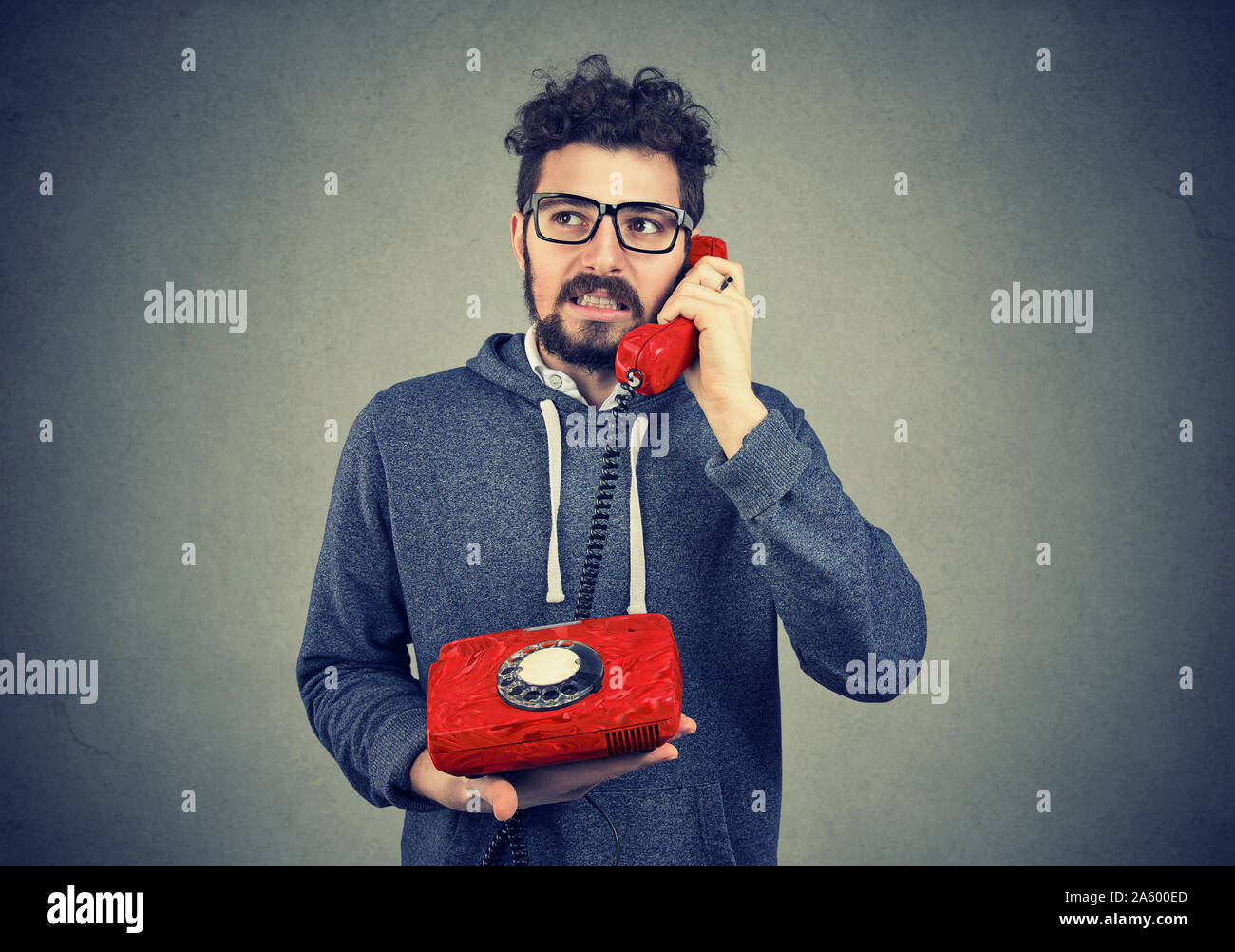 Infastiditi uomo parlando su un vecchio telefono, orinato con lunghi tempi di attesa per il servizio clienti Foto Stock