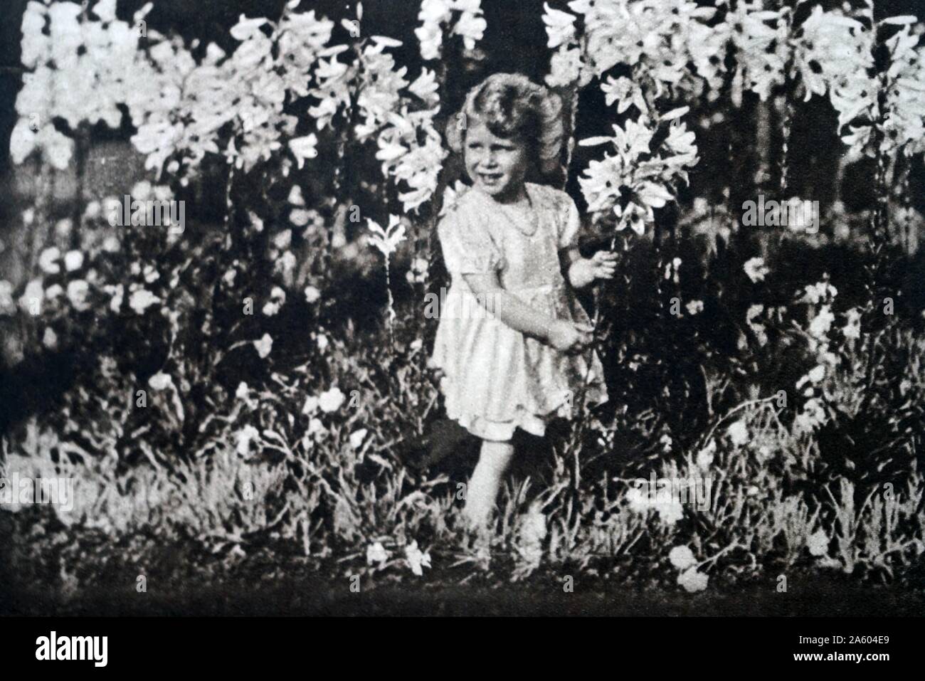 Fotografia di una giovane principessa Elisabetta (1926-) la sorella della Principessa Margaret (1930-2002) e futura Regina, giocando tra fiori. In data xx secolo Foto Stock