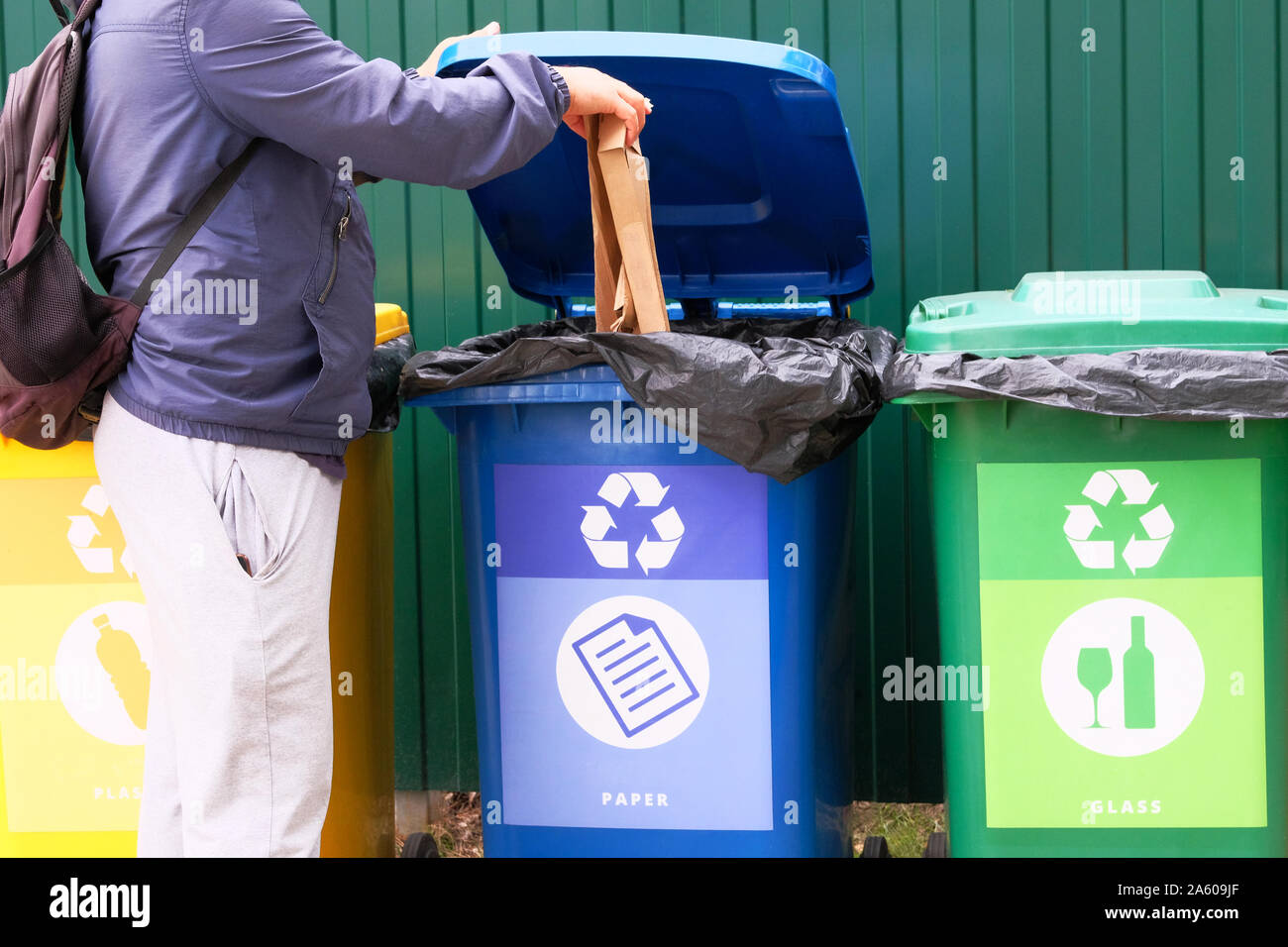 Gettare il cartone in un contenitore per il riciclaggio. Contenitori di metallo, vetro, carta, prodotti organici, in plastica per un ulteriore trattamento di rifiuti. Abito separato Foto Stock
