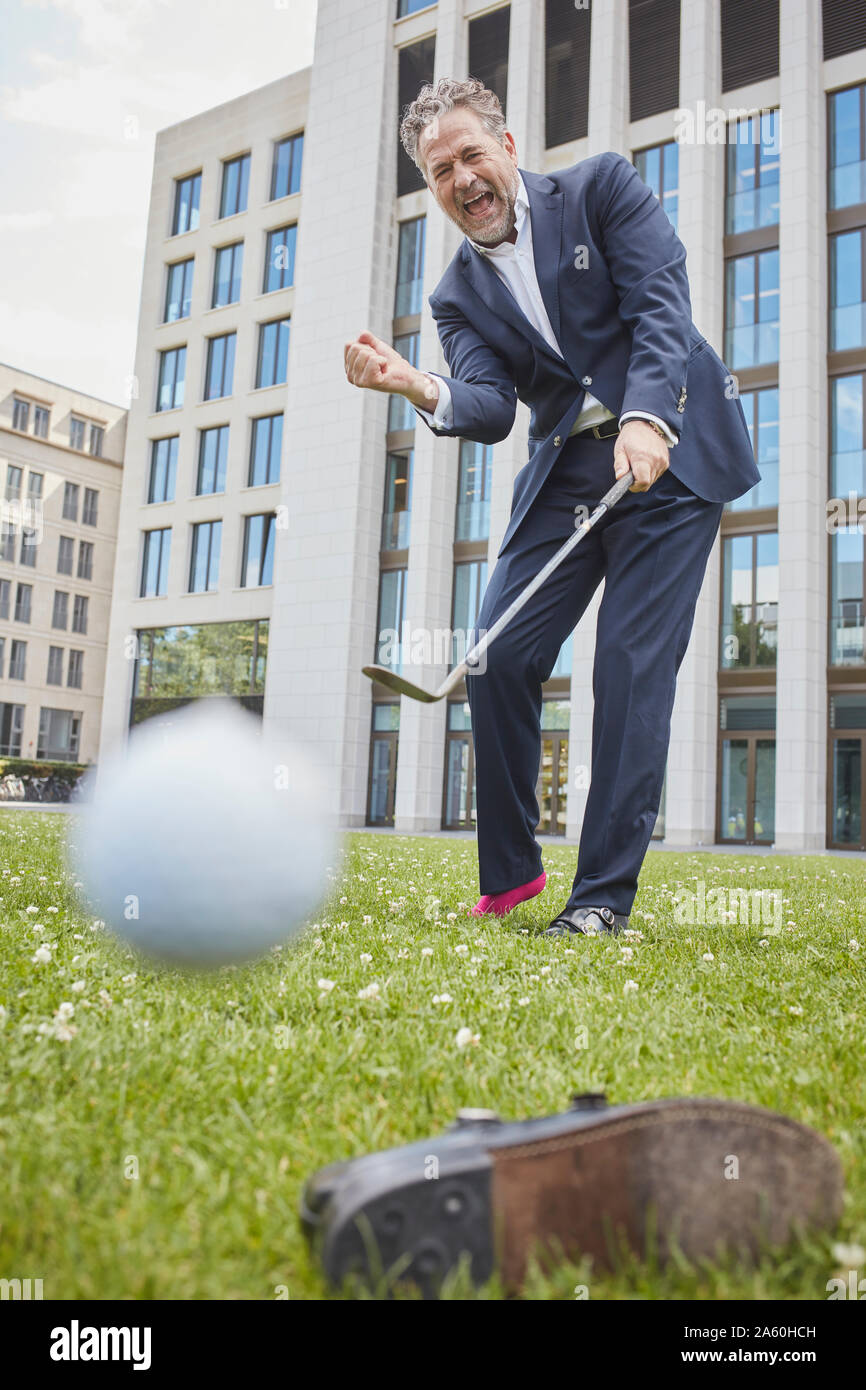 Happy businessman maturo per giocare a golf sul prato in città Foto Stock