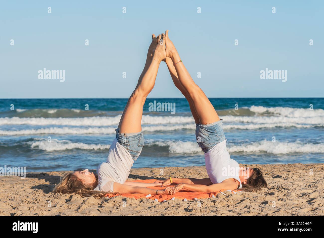 Due donne praticing Acro Yoga sulla spiaggia Foto Stock