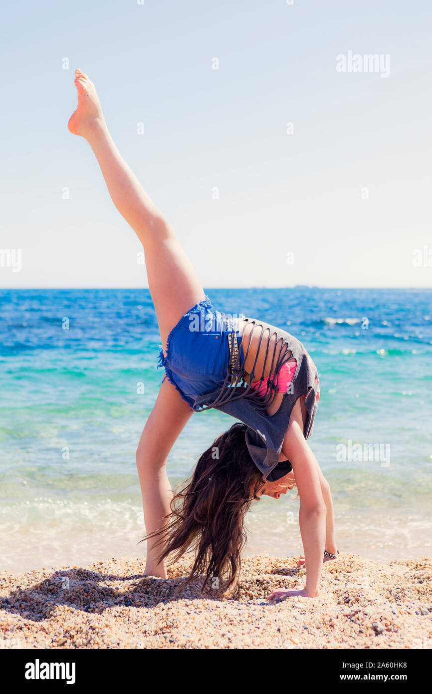 Ragazza facendo ginnastica sulla spiaggia Foto Stock