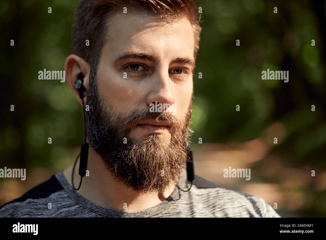 Ritratto di uomo sportivo con gli auricolari in foresta Foto Stock