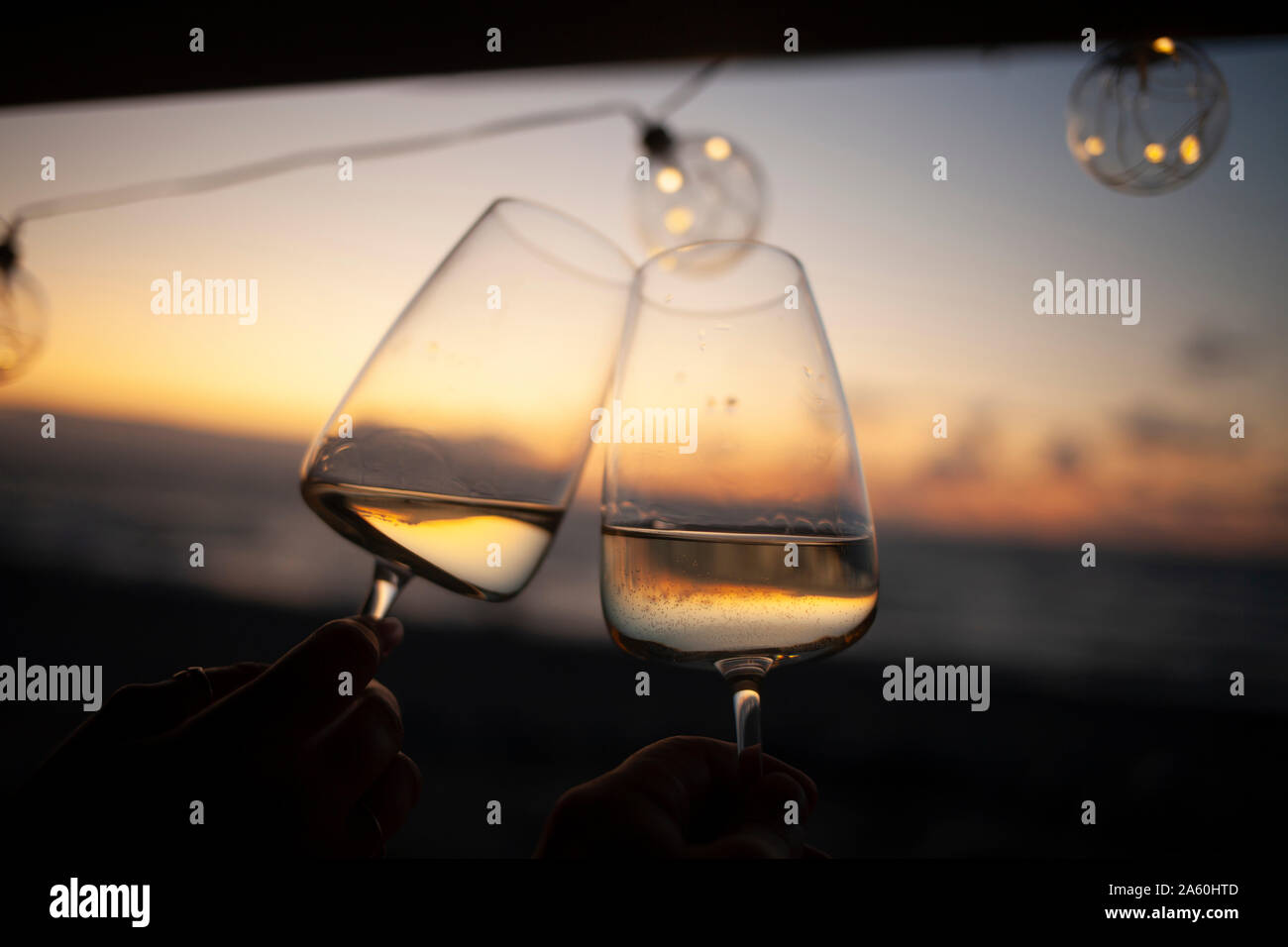 Donna che mantiene due bicchieri di vino bianco in van al tramonto Foto Stock