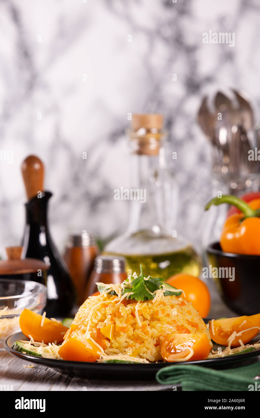 Riso cotto con carote e peperoni sul tavolo della cucina Foto Stock