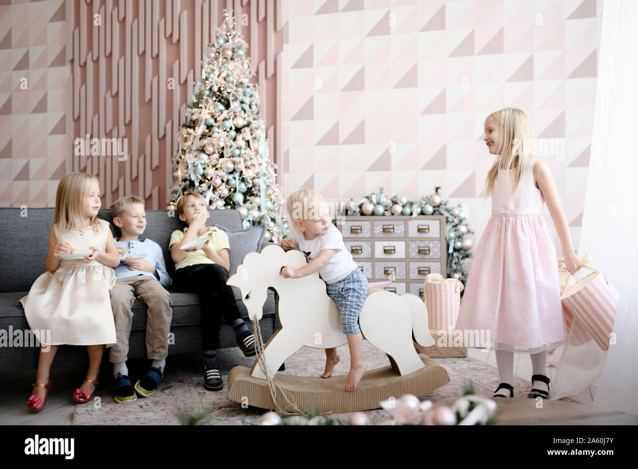 Cinque bambini che giocano e mangiare i cookie nel soggiorno al tempo di Natale Foto Stock