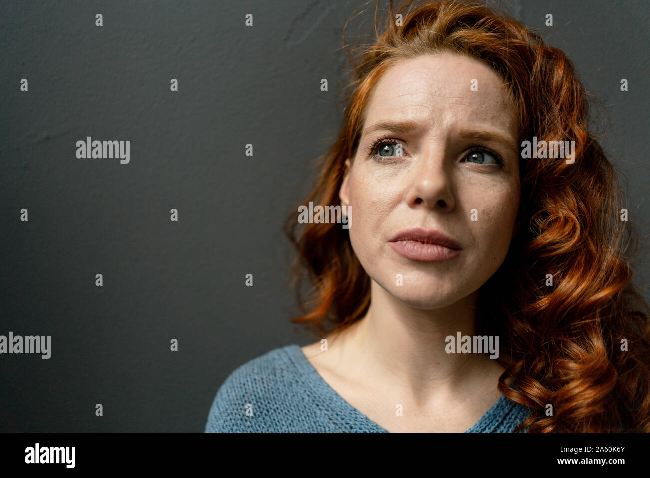 Ritratto di pensieroso redheaded donna contro uno sfondo grigio Foto Stock