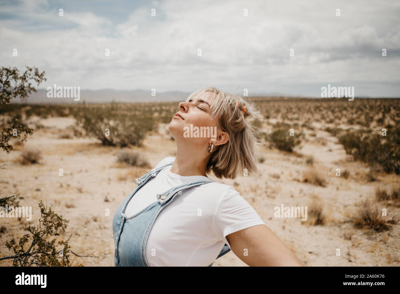 Giovane donna nel paesaggio desertico con gli occhi chiusi, Joshua Tree National Park, California, Stati Uniti d'America Foto Stock