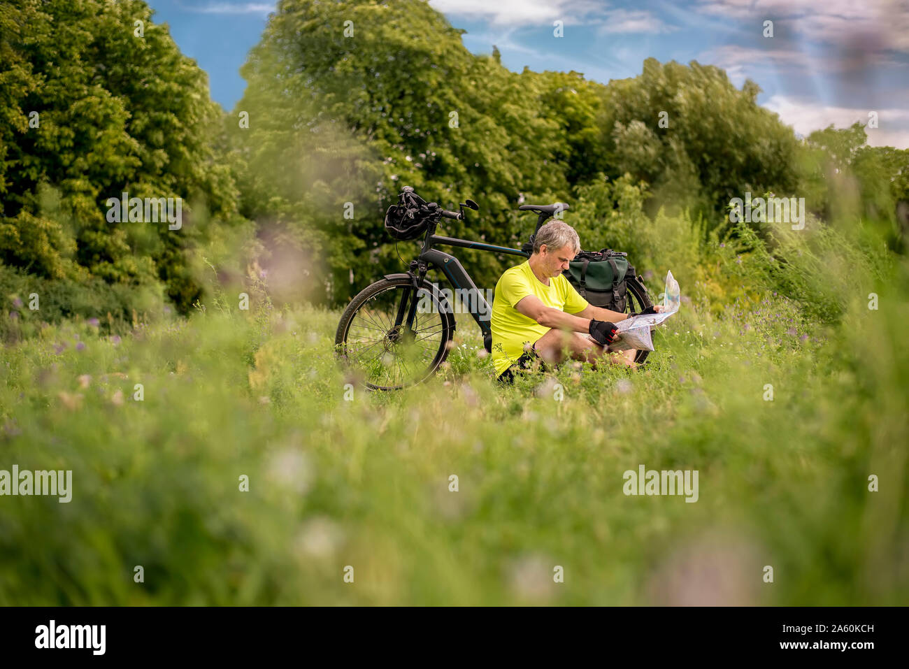 Uomo maturo per una pausa e guardando una mappa durante il suo tour in bicicletta con la bicicletta elettrica Foto Stock