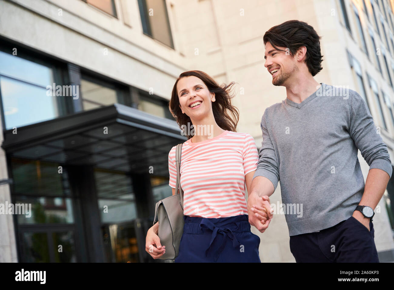 Coppia felice camminando mano nella mano in città Foto Stock