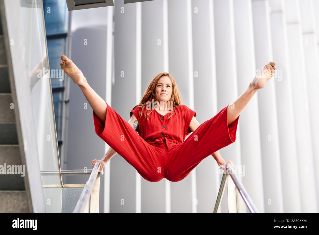Sporty giovane donna facendo acrobazie su una ringhiera Foto Stock