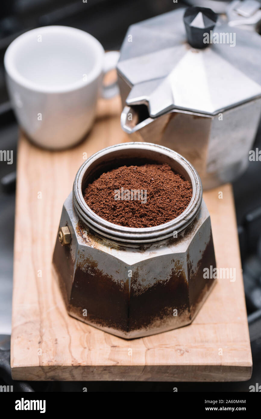 Angolo di alta vista di caffè macinato con contenitore a tazza e maker sul vassoio in legno in cucina Foto Stock