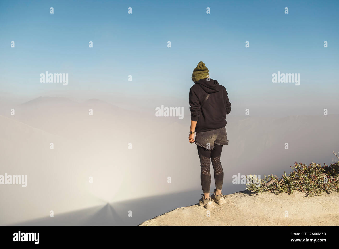 Giovane donna in piedi sul bordo del vulcano Ijen, Java, Indonesia Foto Stock