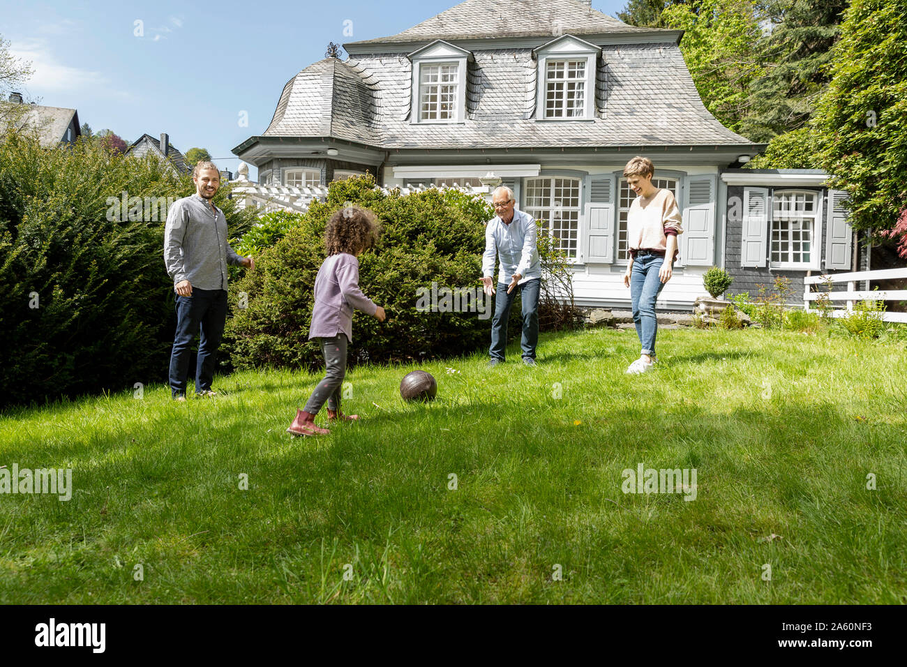 Felice famiglia estesa a giocare a calcio in giardino Foto Stock