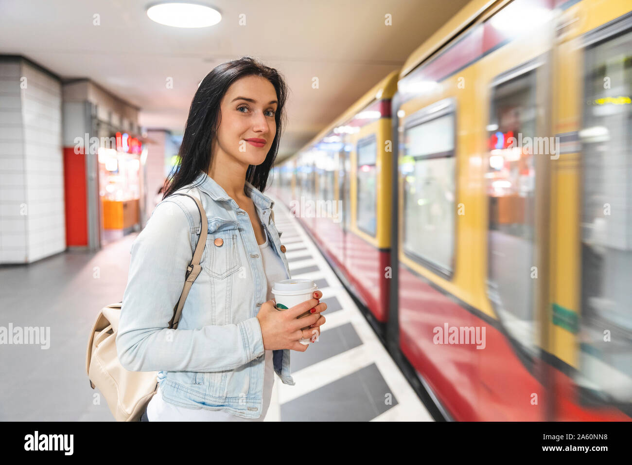 Giovane donna alla stazione della metropolitana di attesa per il treno, Berlino, Germania Foto Stock