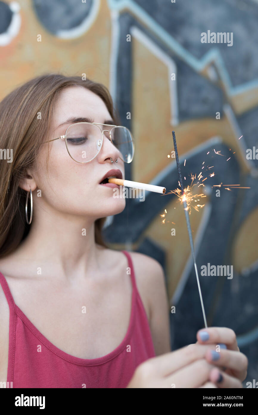 Giovane donna sigaretta di illuminazione con un sparkler Foto Stock