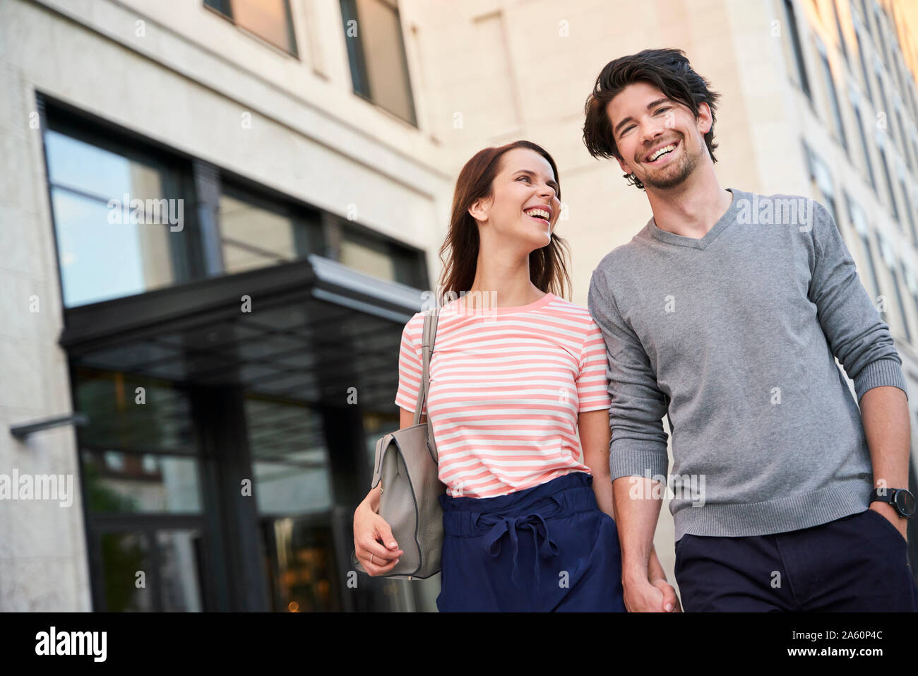 Coppia felice camminando mano nella mano in città Foto Stock