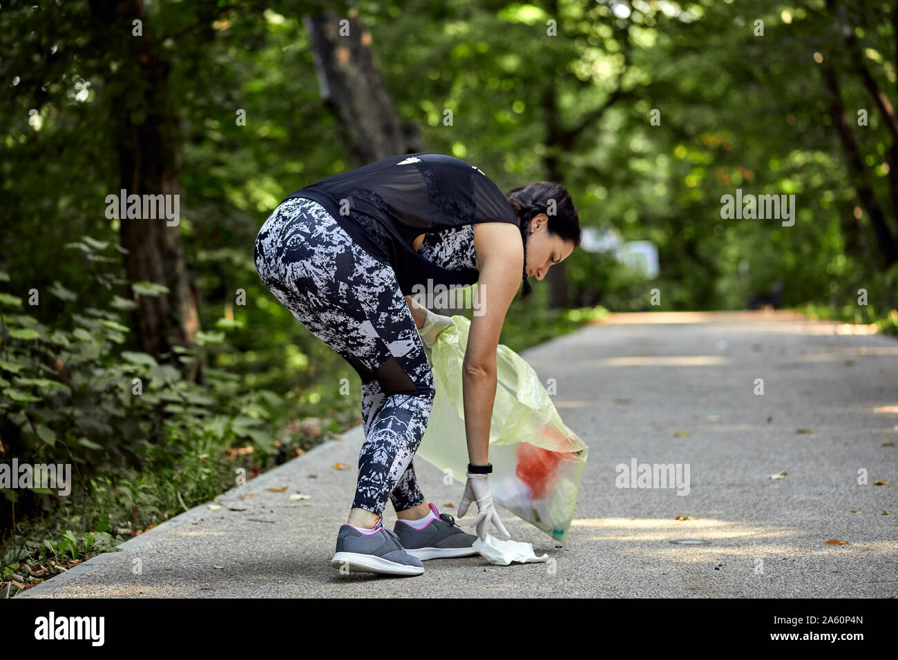 Giovane donna plogging sulla strada forestale Foto Stock