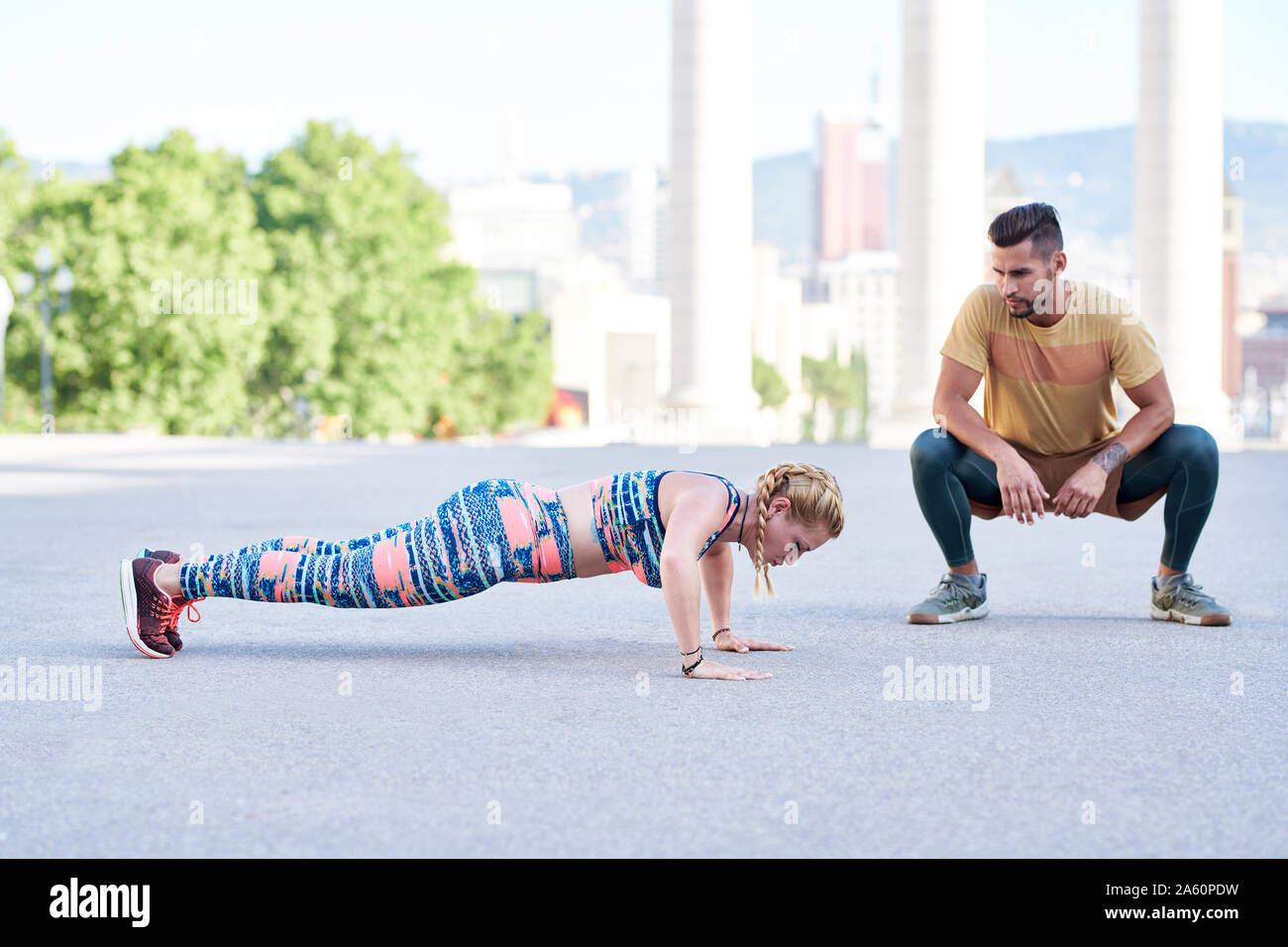 Fitness coach pratica con la giovane donna all'aperto nella città Foto Stock