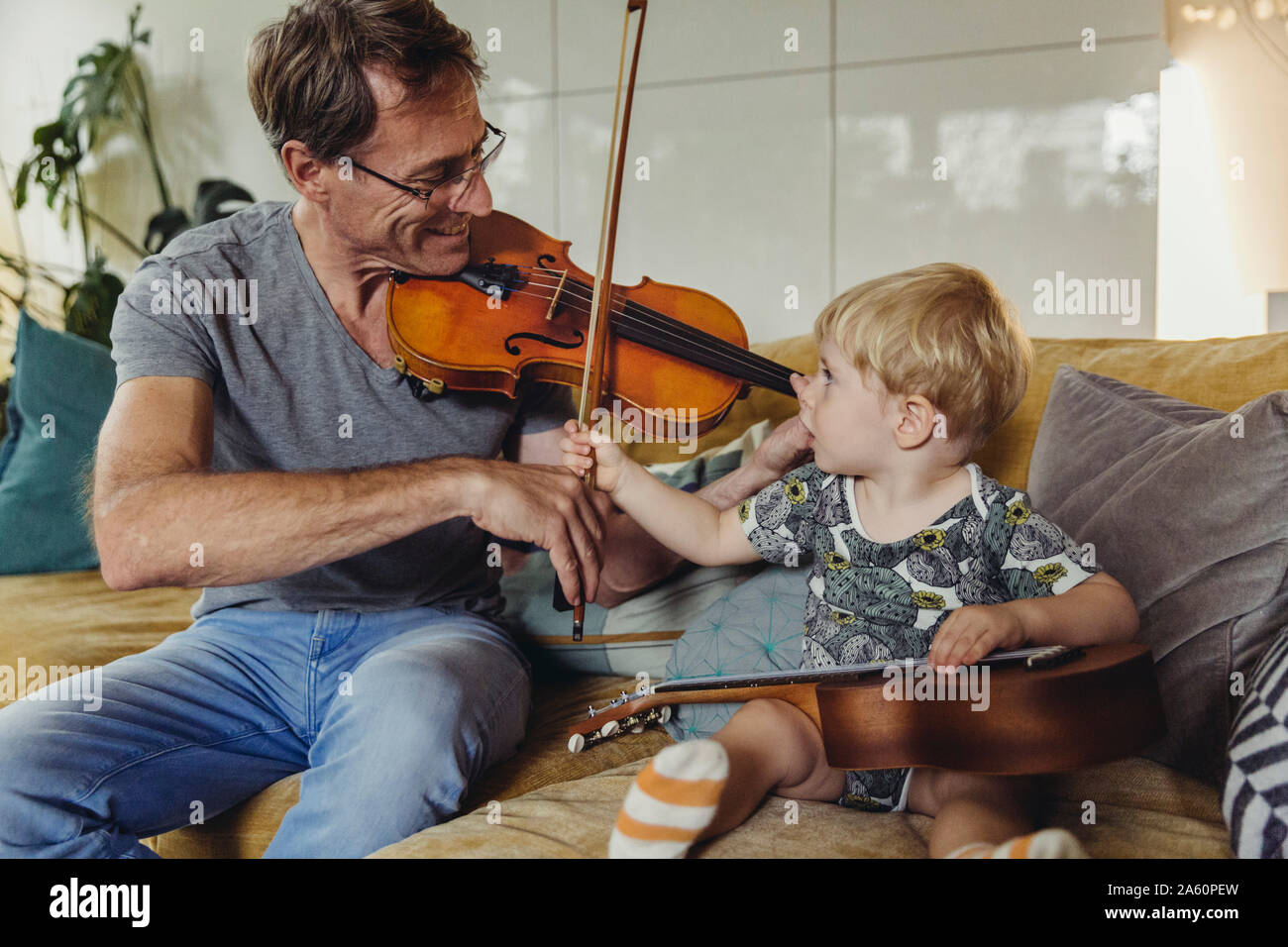Il Toddler guardando suo padre suona il violino Foto Stock