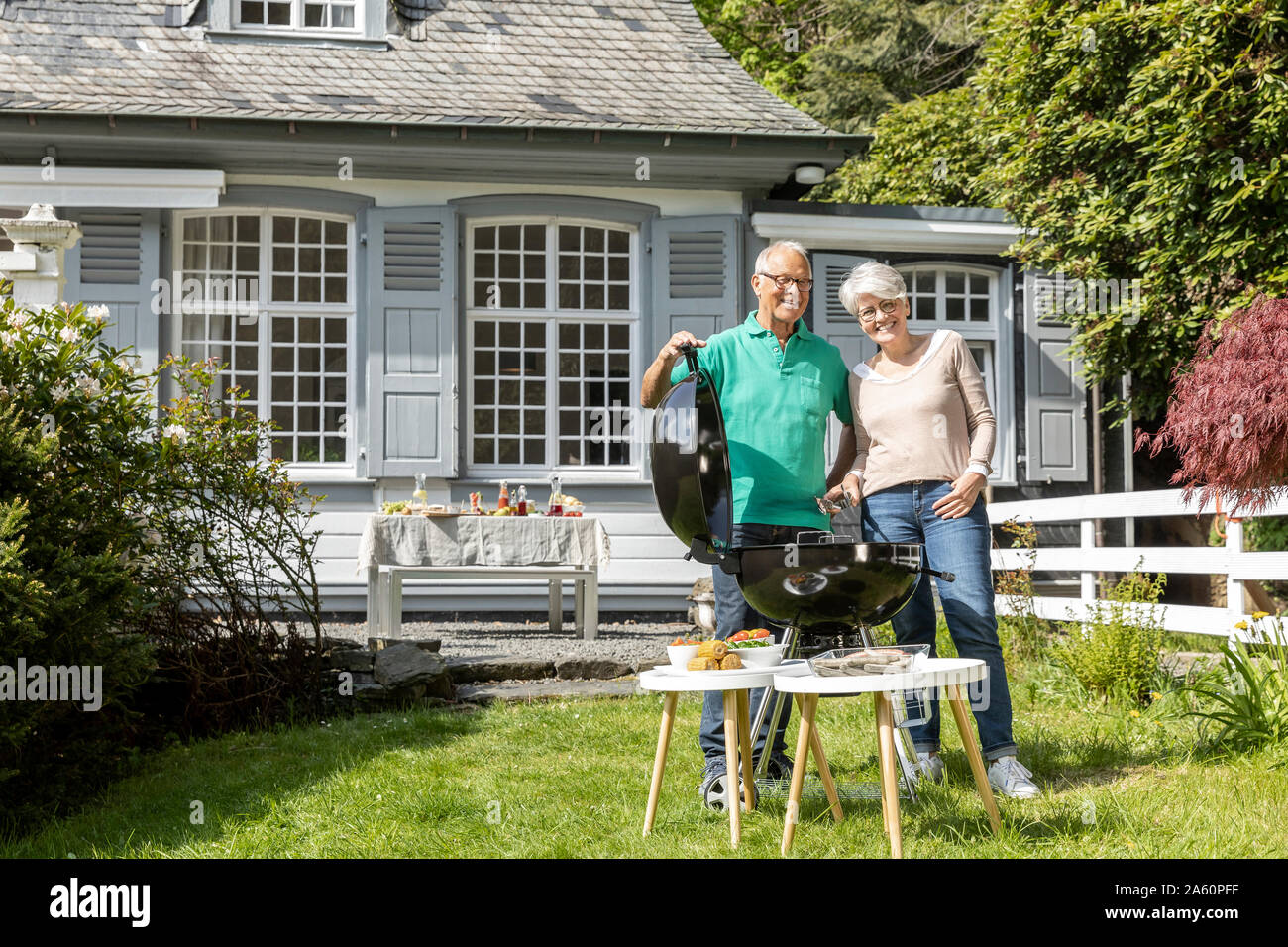 Felice coppia senior avente un barbecue nel giardino della loro casa Foto Stock